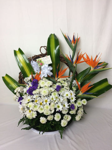 Corona fúnebre hecha con rosas, lirios, flores blancas silvestres, aves del paraíso y follajes verdes.