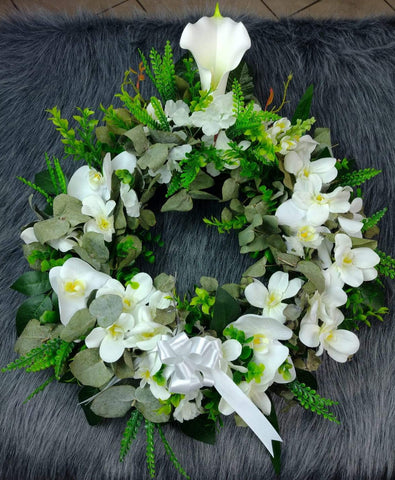 Corona fúnebre con rosas y flores blancas artificiales.