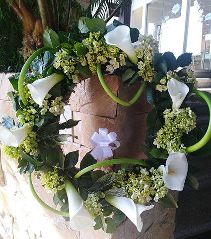Corona de flores naturales, confeccionada con hortensias, cartuchos y follajes verdes.