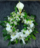 Corona fúnebre hecha con flores artificiales, orquídeas de color blanco, cartuchos y follajes verdes.