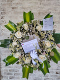 Linda corona fúnebre hecha con rosas blancas y eucaliptos.