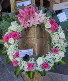 Corona fúnebre hecha con flores blancas, rosadas y fucsias