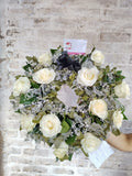 Preciosa corona fúnebre hecha con rosas blancas y eucaliptos.