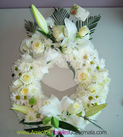 Corona de flores naturales blancas con follaje verde.
