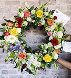 Corona fúnebre hecha con rosas y variedad flores naturales