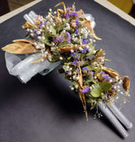 Cruz plateada con flores artificiales lilas y verdes