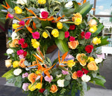 Corona fúnebre hecha con flores con rosas amarillas y rojas.