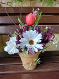 Maceta de barro hecha con bellas flores artificiales: gerberas y tulipanes