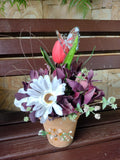 Maceta de barro hecha con flores artificiales: gerberas y tulipanes.